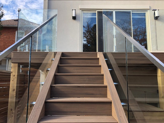 Light brown PVC decking with stairs and glass railing in one of Toronto`s backyards