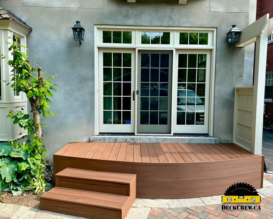A brown composite deck with stairs and no railing 