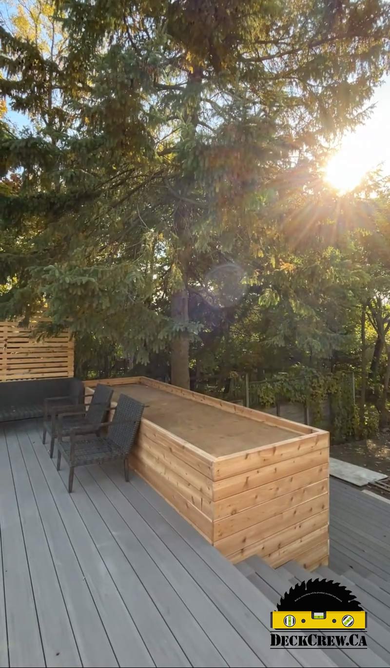 Grey composite deck with stairs and a cedar planter