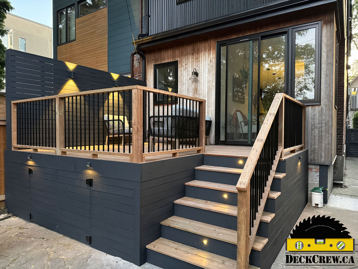 Custom backyard deck with stairs, railing, and integrated lighting in Roncesvalles, Toronto