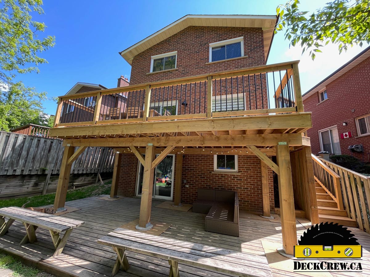 Elevated pressure-treated lumber deck with wood posts, stairs, and railing, built for a residential backyard.