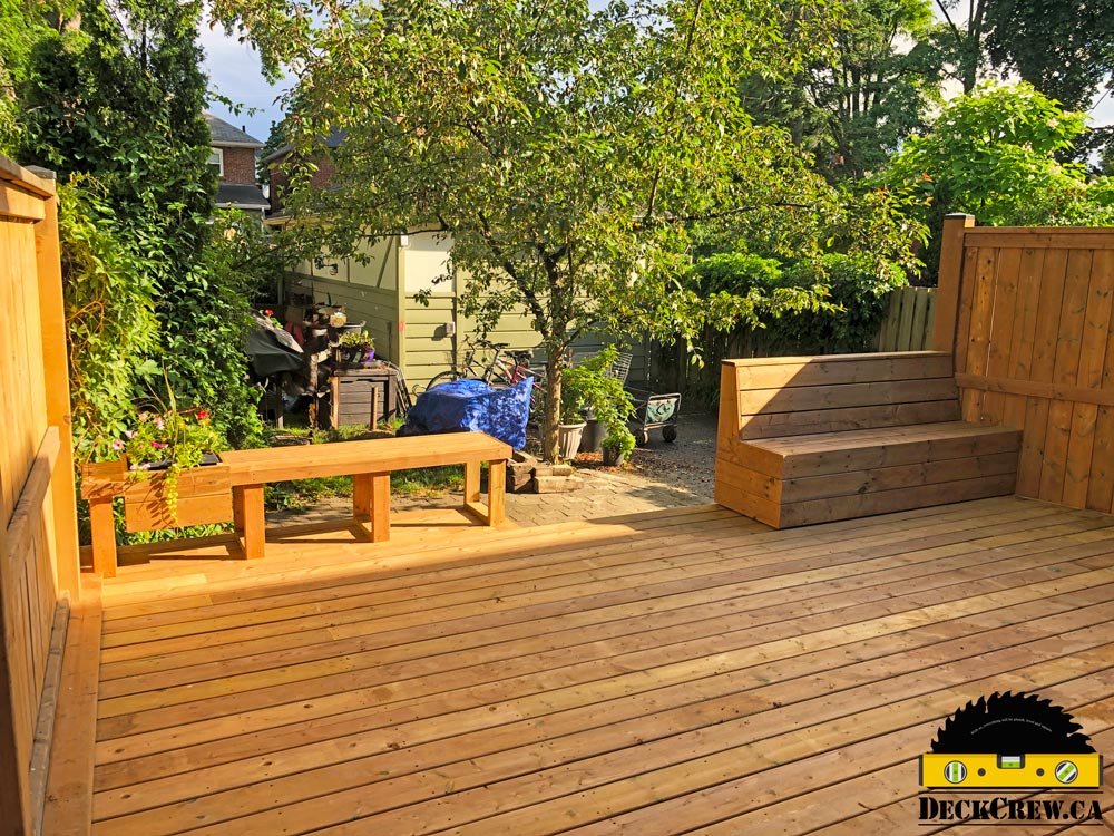 Pressure-treated deck in Bloor West Village with two built-in benches, wood privacy screens and a planter overlooking the garden.
