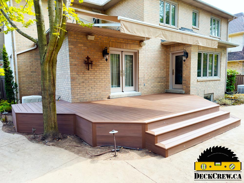 English Walnut TimberTech PVC deck with wide steps and an angled edge beside a mature tree at an Etobicoke home.
